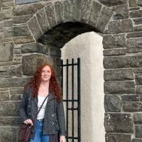 Alum standing beside stone wall and gate